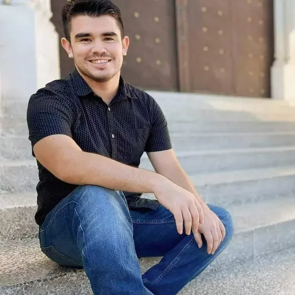Un joven sentado en los escalones de un edificio.