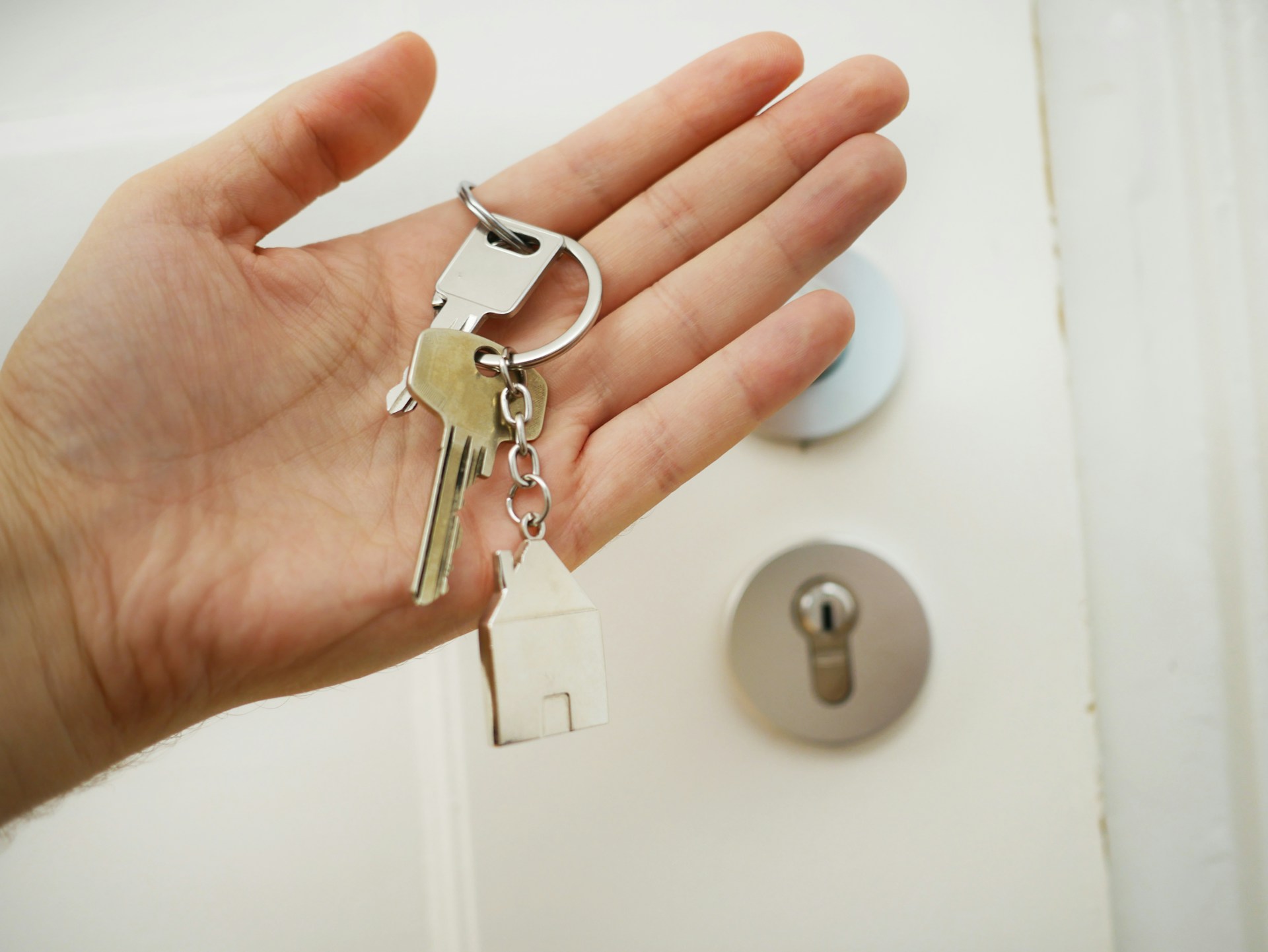 Una mano que sostiene un juego de llaves con un llavero con forma de casa frente a la cerradura de una puerta, que simboliza cuán efectivo el SEO para inmobiliarias puede abrir puertas para aumentar la visibilidad en línea.