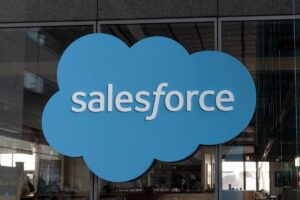 Gran logotipo de Salesforce en forma de nube azul montado en el cristal exterior de un edificio de oficinas.
