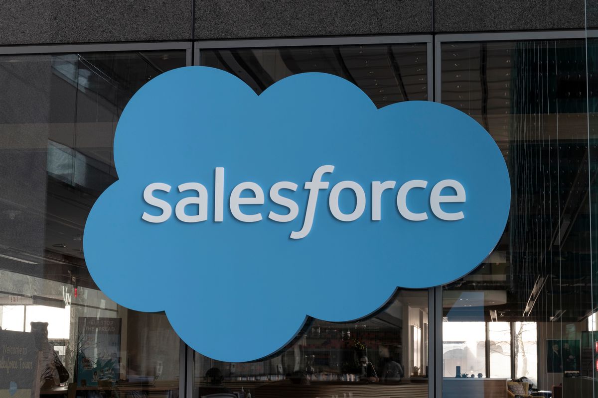 Gran logotipo de Salesforce en forma de nube azul montado en el cristal exterior de un edificio de oficinas.