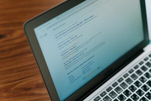Sobre una superficie de madera descansa un ordenador portátil que muestra una página de resultados de búsqueda en Google de "mejores servicios de canguro 2023".