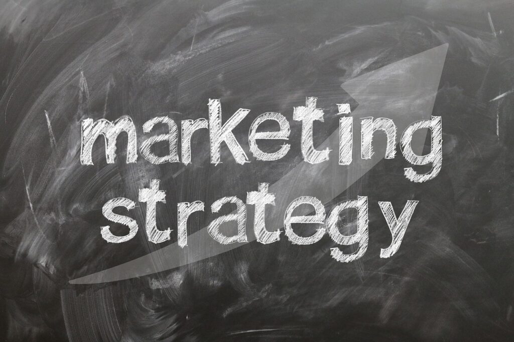Las palabras "estrategia de marketing" están escritas con tiza blanca en una pizarra con una gran flecha apuntando a la derecha en el fondo.
