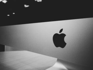 Primer plano de un logotipo de Apple en la parte frontal de un ordenador Apple plateado, fotografiado en blanco y negro.