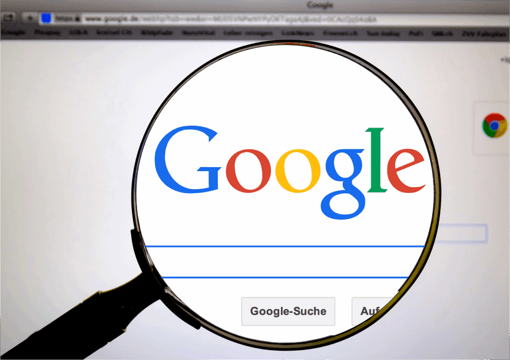 Inicio 8 Una lupa enfoca el logotipo de Google que aparece en la pantalla de un ordenador con la barra de búsqueda visible.
