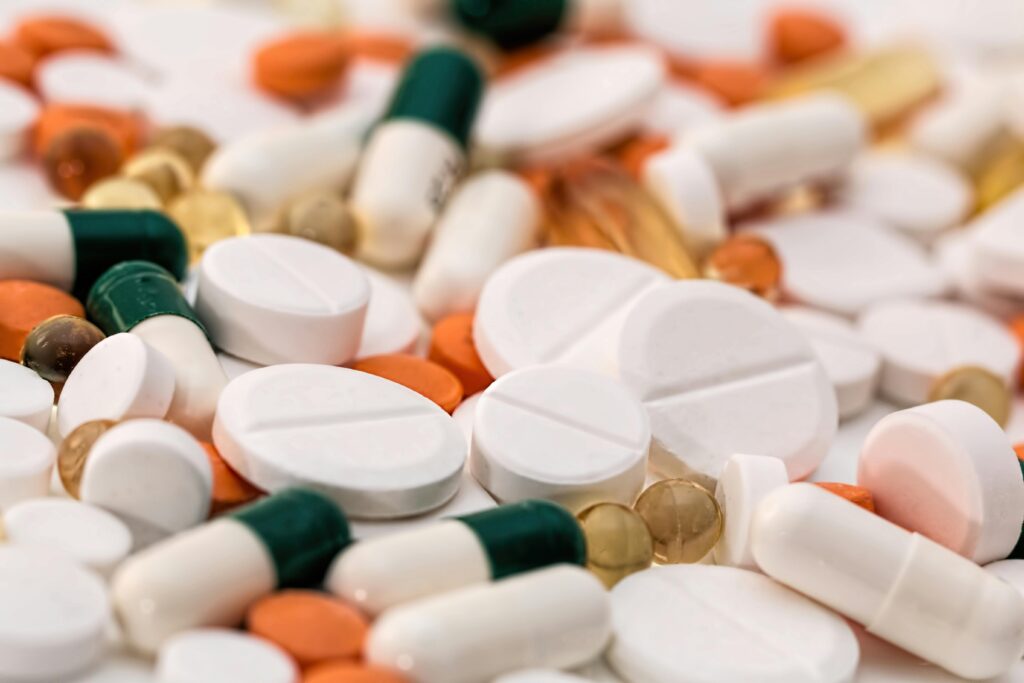 Inicio 8 Una variedad de pastillas y cápsulas de diferentes formas, tamaños y colores esparcidas por una superficie.