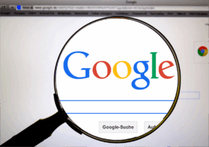 Una lupa enfoca el logotipo de Google que aparece en la pantalla de un ordenador con la barra de búsqueda visible.