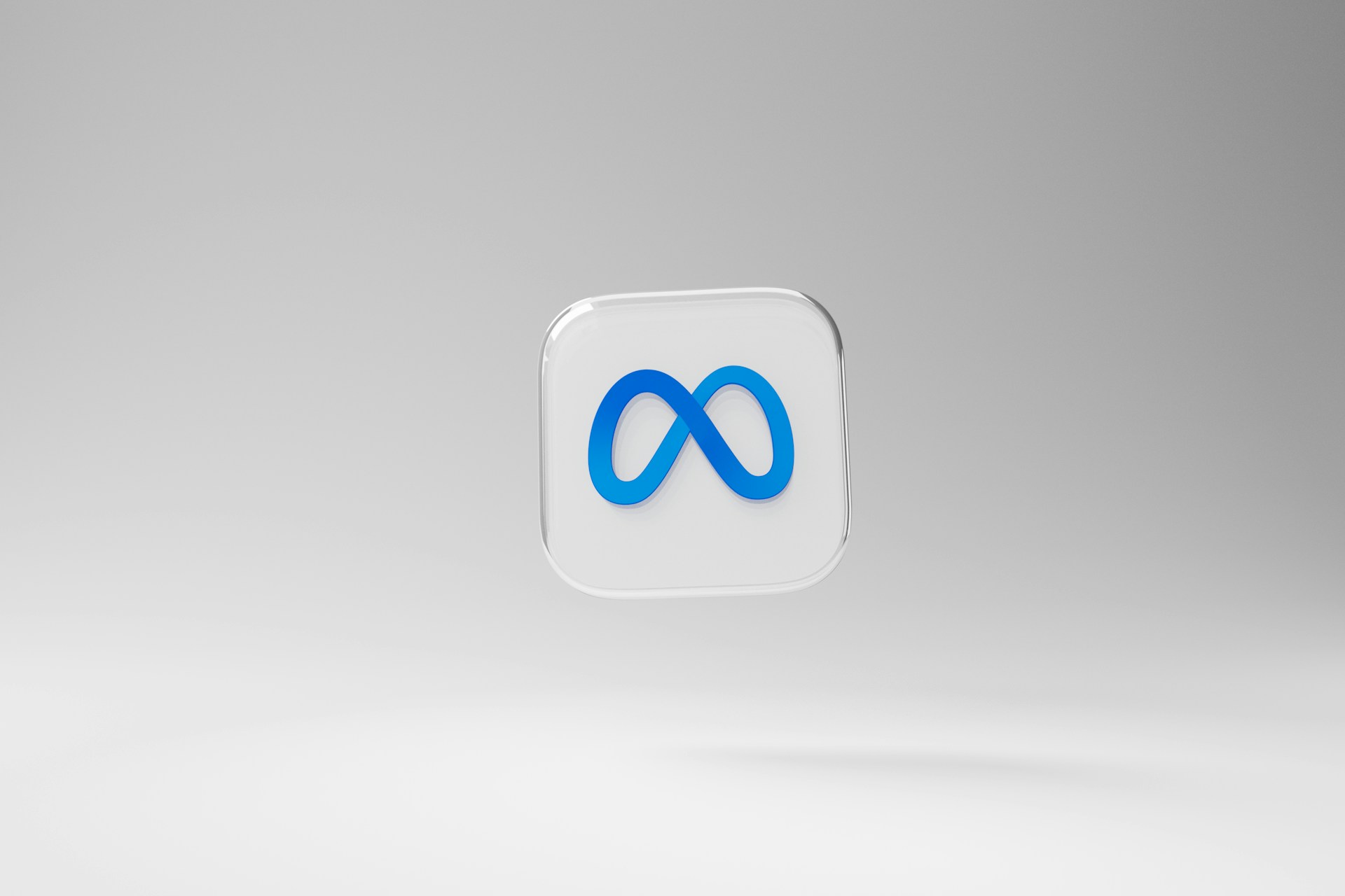 Un logotipo Meta en 3D, con un símbolo de infinito azul sobre un cuadrado blanco redondeado, flota sobre un fondo liso gris claro.