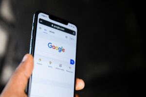 Una mano sostiene un smartphone que muestra la página de inicio de búsqueda de Google en un navegador web.