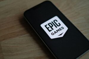 Un smartphone que muestra el logotipo de Epic Games en su pantalla, colocado sobre una superficie de madera.