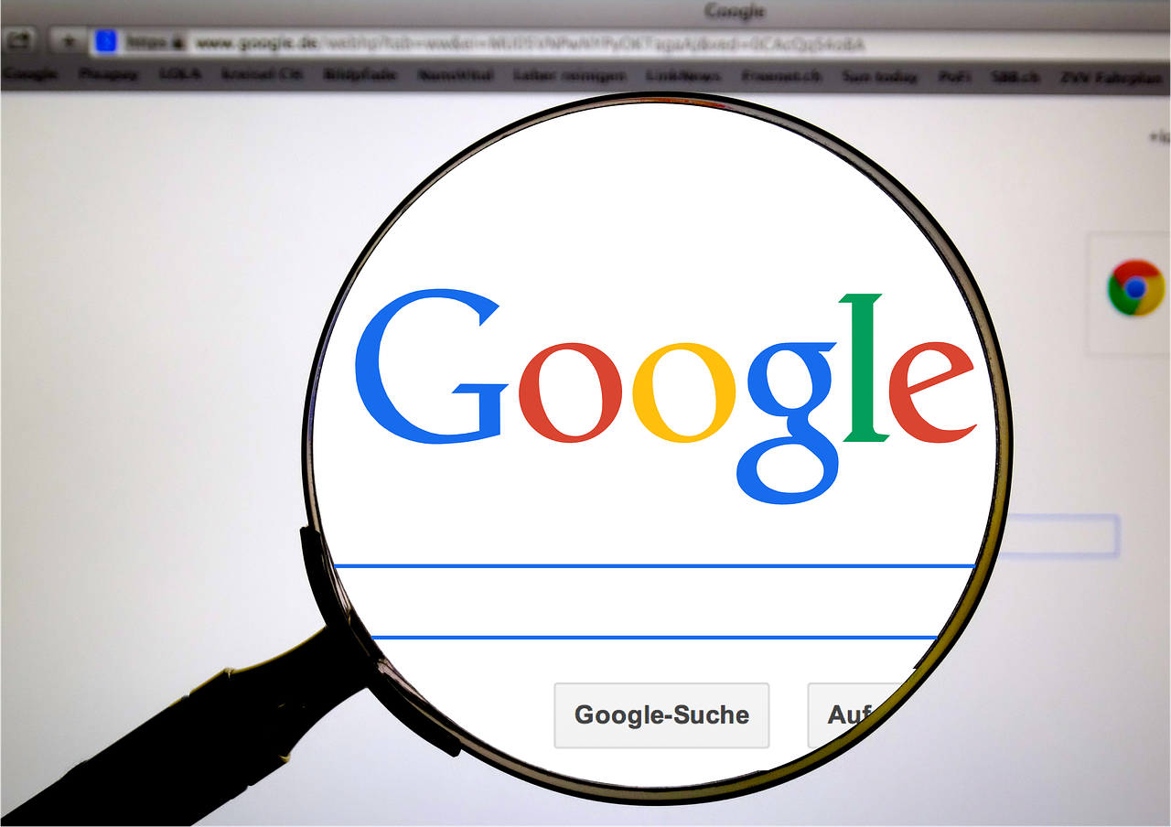 Una lupa enfoca el logotipo de Google que aparece en la pantalla de un ordenador con la barra de búsqueda visible.