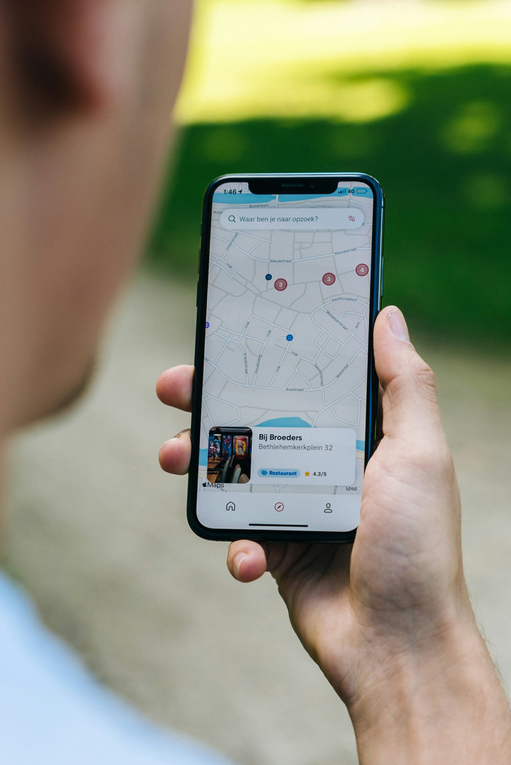 Una persona sostiene un teléfono inteligente en el que aparece una aplicación de mapas con una ubicación localizada y un negocio cercano.