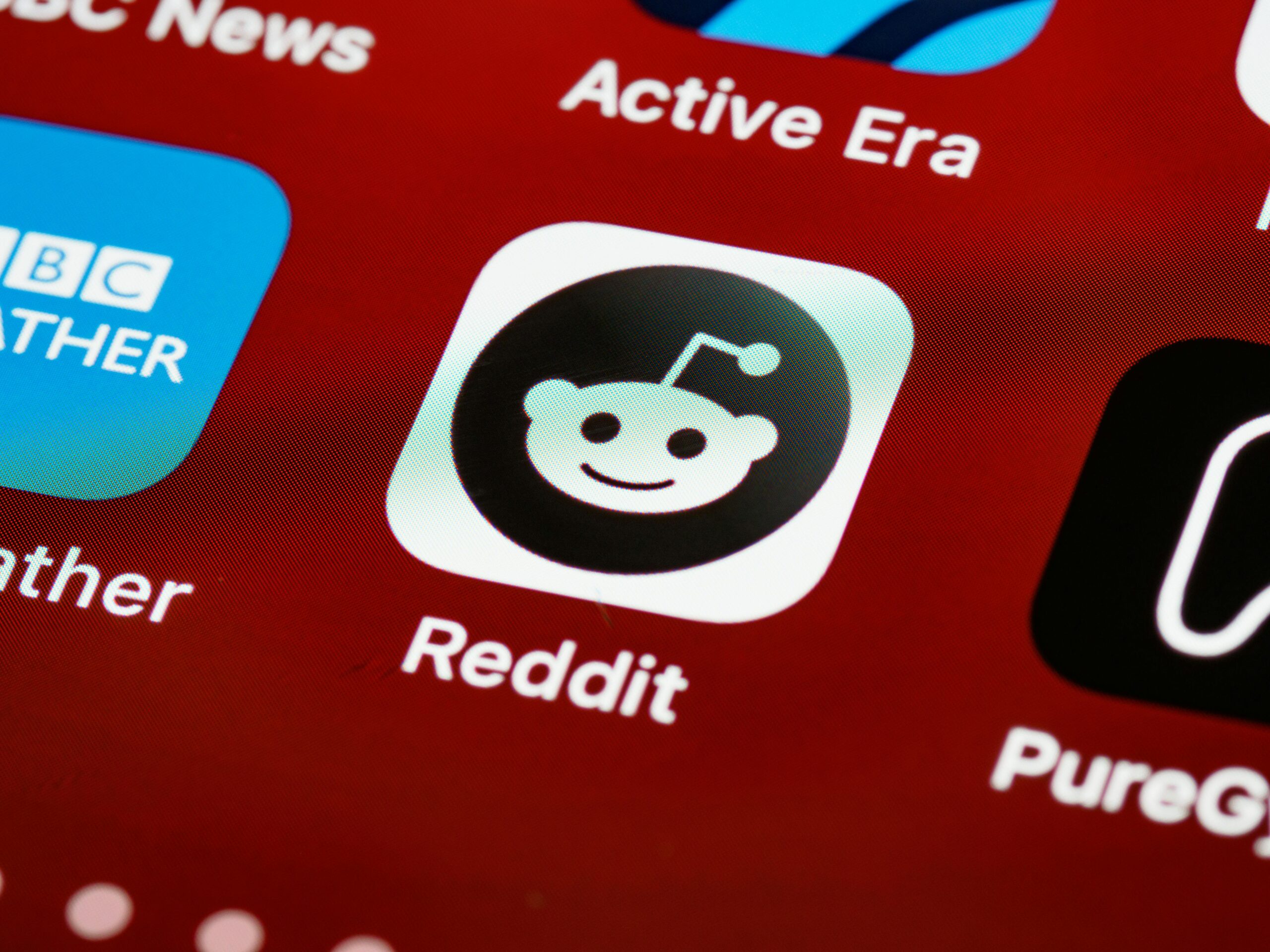 Primer plano del icono de la aplicación Reddit mostrado en la pantalla de un smartphone entre otros iconos de aplicaciones.