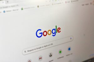 La pantalla de un ordenador muestra la página principal de Google en portugués, con la barra de búsqueda y los iconos de varias aplicaciones de Google.