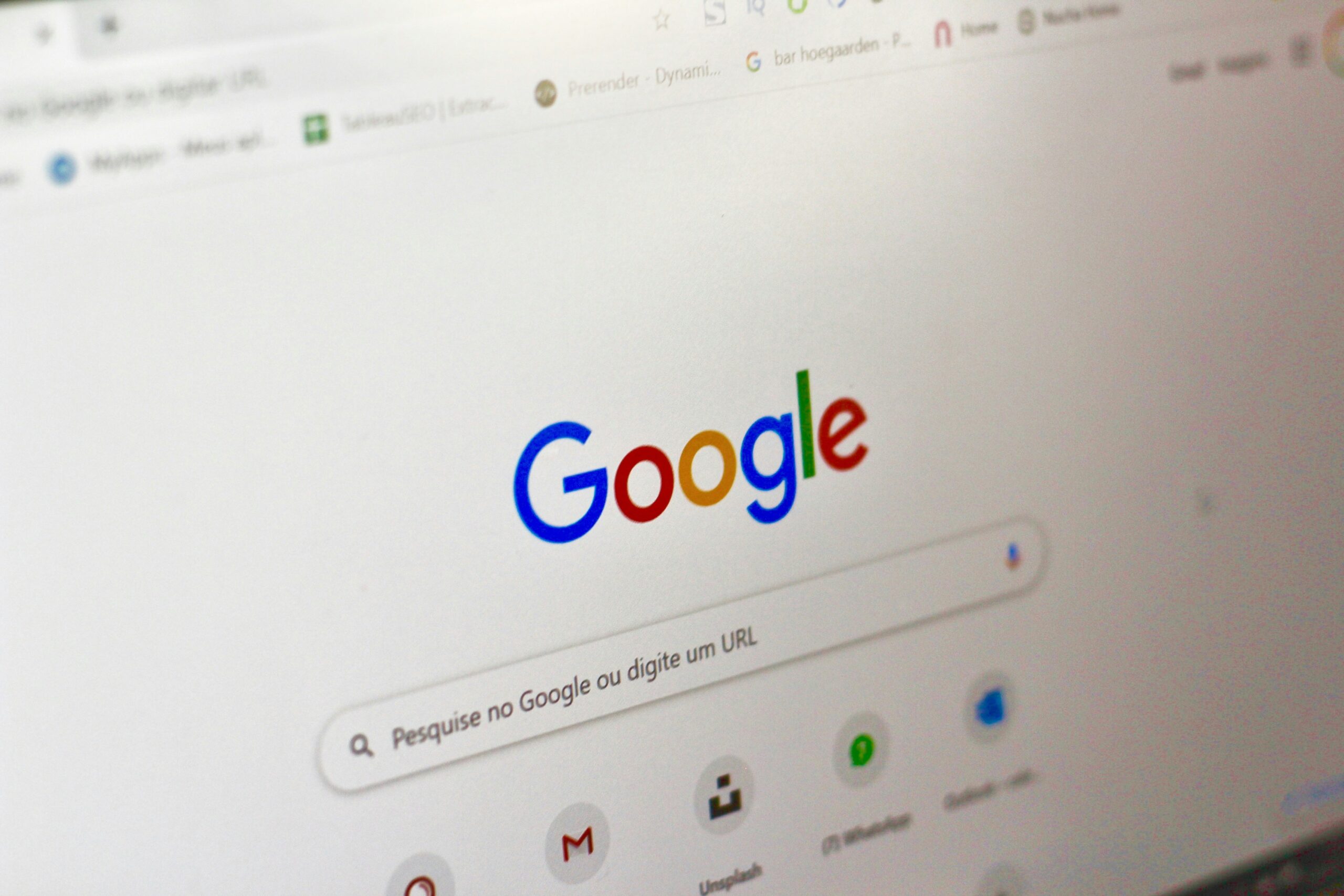 La pantalla de un ordenador muestra la página principal de Google en portugués, con la barra de búsqueda y los iconos de varias aplicaciones de Google.