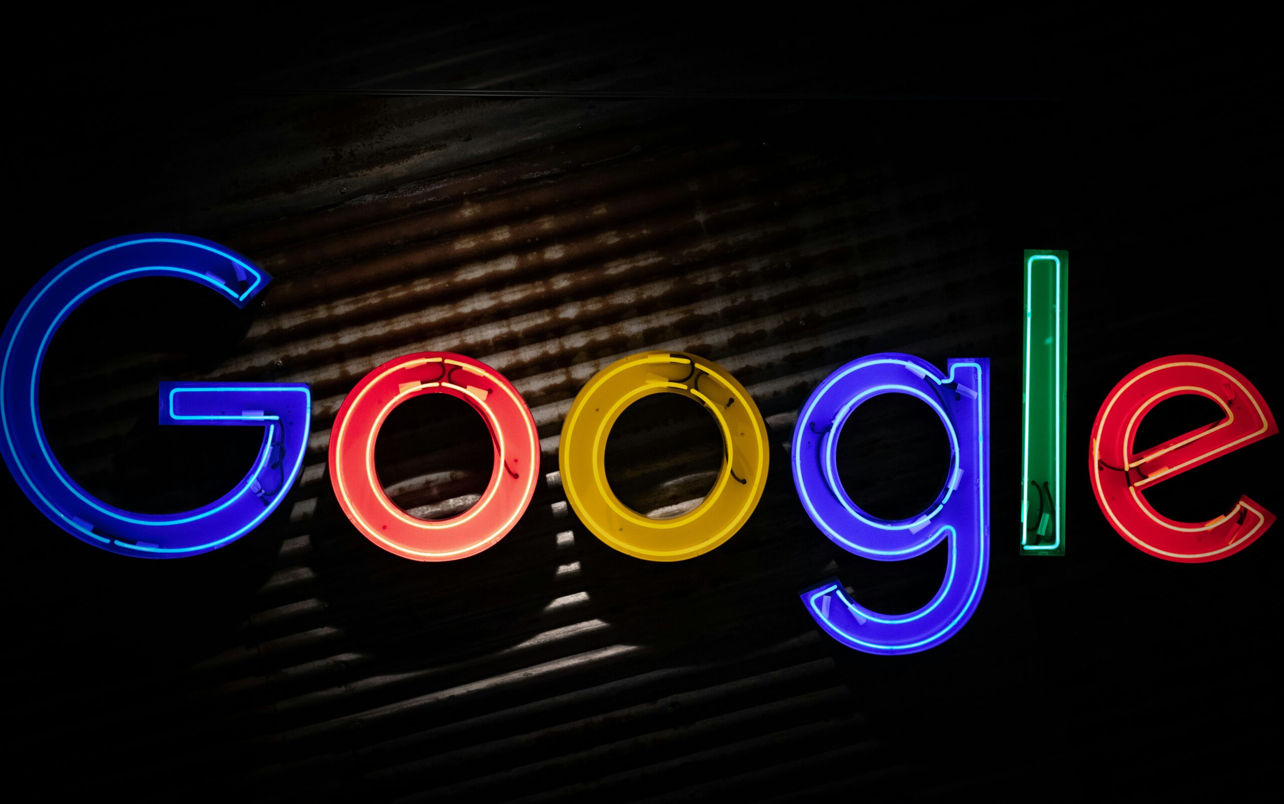 Cartel de neón que muestra la palabra "Google" en las características letras multicolores de la empresa sobre un fondo oscuro.