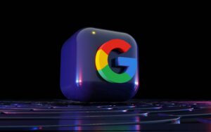 Un cubo negro en 3D con el logotipo de Google "G" en rojo, azul, amarillo y verde se asienta sobre una superficie futurista reflectante sobre un fondo oscuro.