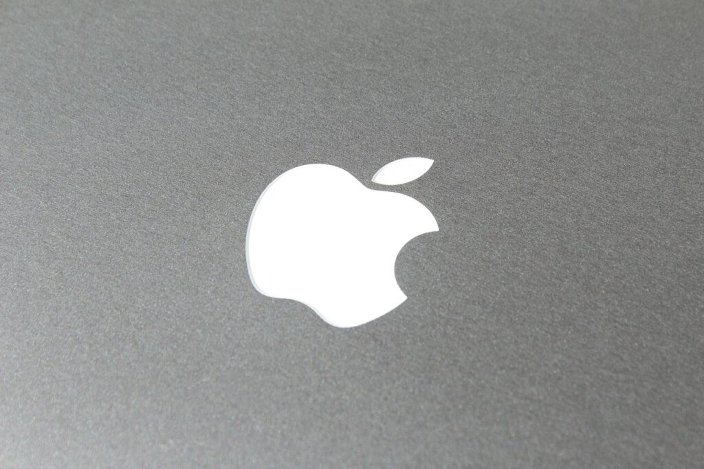 Primer plano de un logotipo de Apple blanco sobre una superficie gris metálica.