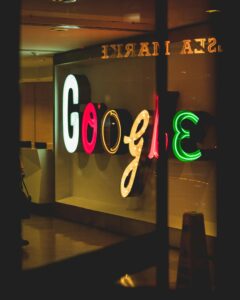 Un rótulo de Google brillantemente iluminado en varios colores se muestra detrás de un cristal en un entorno interior.