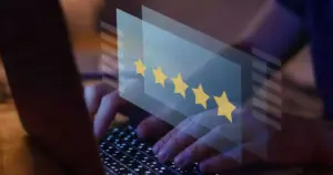Manos escribiendo en un teclado de ordenador portátil con una superposición digital de una calificación de cinco estrellas en amarillo que aparece en la pantalla, destacando la importancia de las reseñas para mejorar el posicionamiento en Google y el SEO Local.