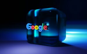 Un cubo azul transparente con el logotipo de Google centrado en su parte frontal, sobre un fondo oscuro con iluminación azul.