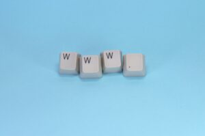 Cuatro teclas blancas dispuestas sobre un fondo azul escriben "www." con tres teclas W seguidas de un punto.