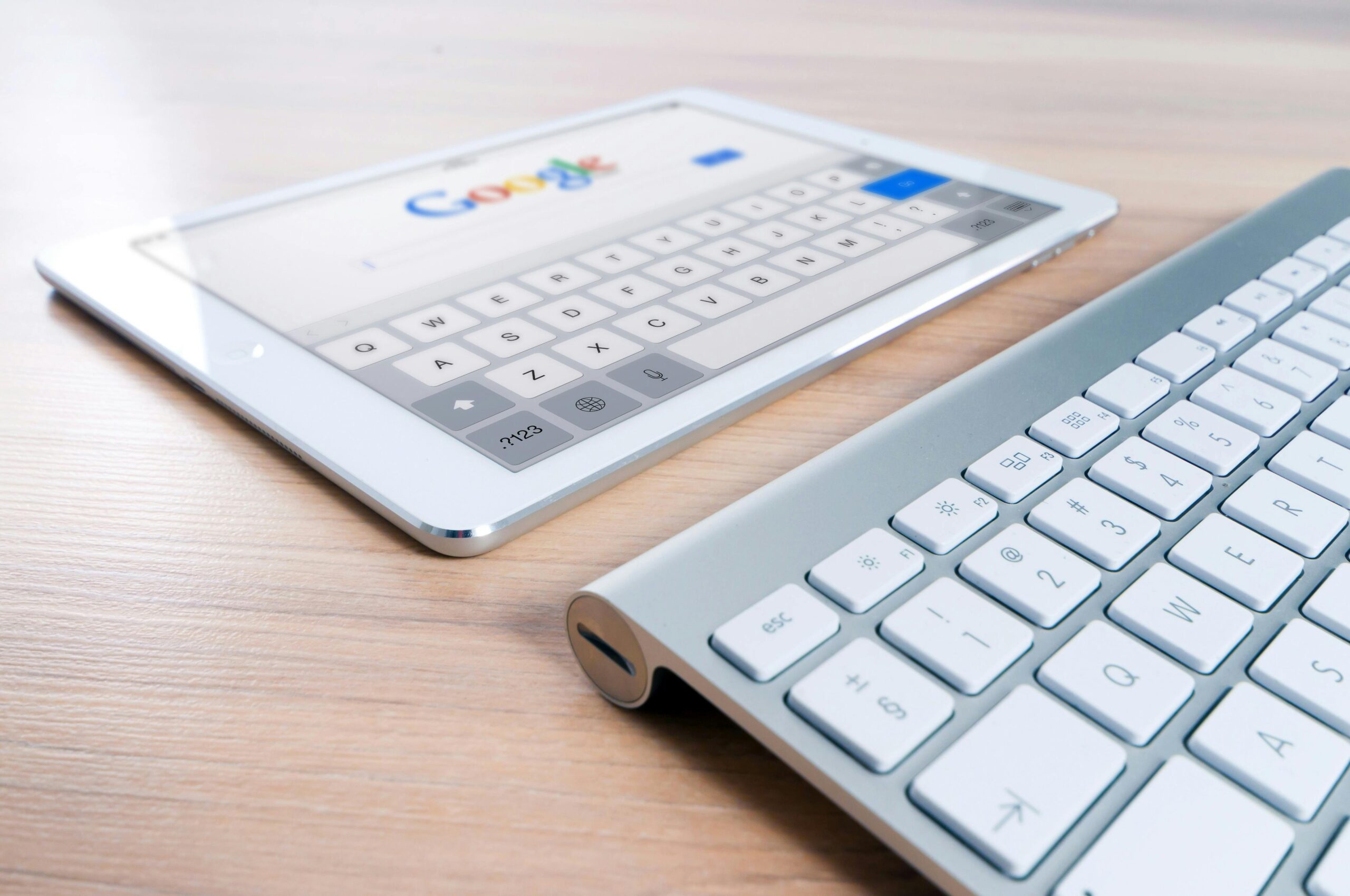 Sobre un escritorio de madera se colocan una tableta con la página de búsqueda de Google y un teclado inalámbrico.