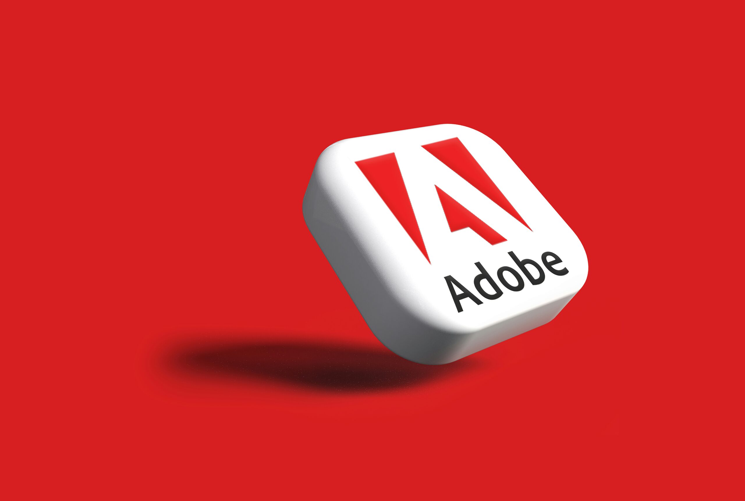 Icono cuadrado en 3D con el logotipo de Adobe y texto sobre fondo rojo, proyectando una suave sombra.