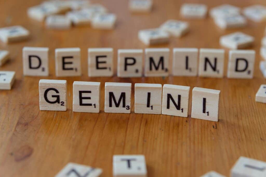 Las fichas de Scrabble sobre una superficie de madera deletrean "DEEPMIND" en la fila de atrás y "GEMINI" en la de delante.