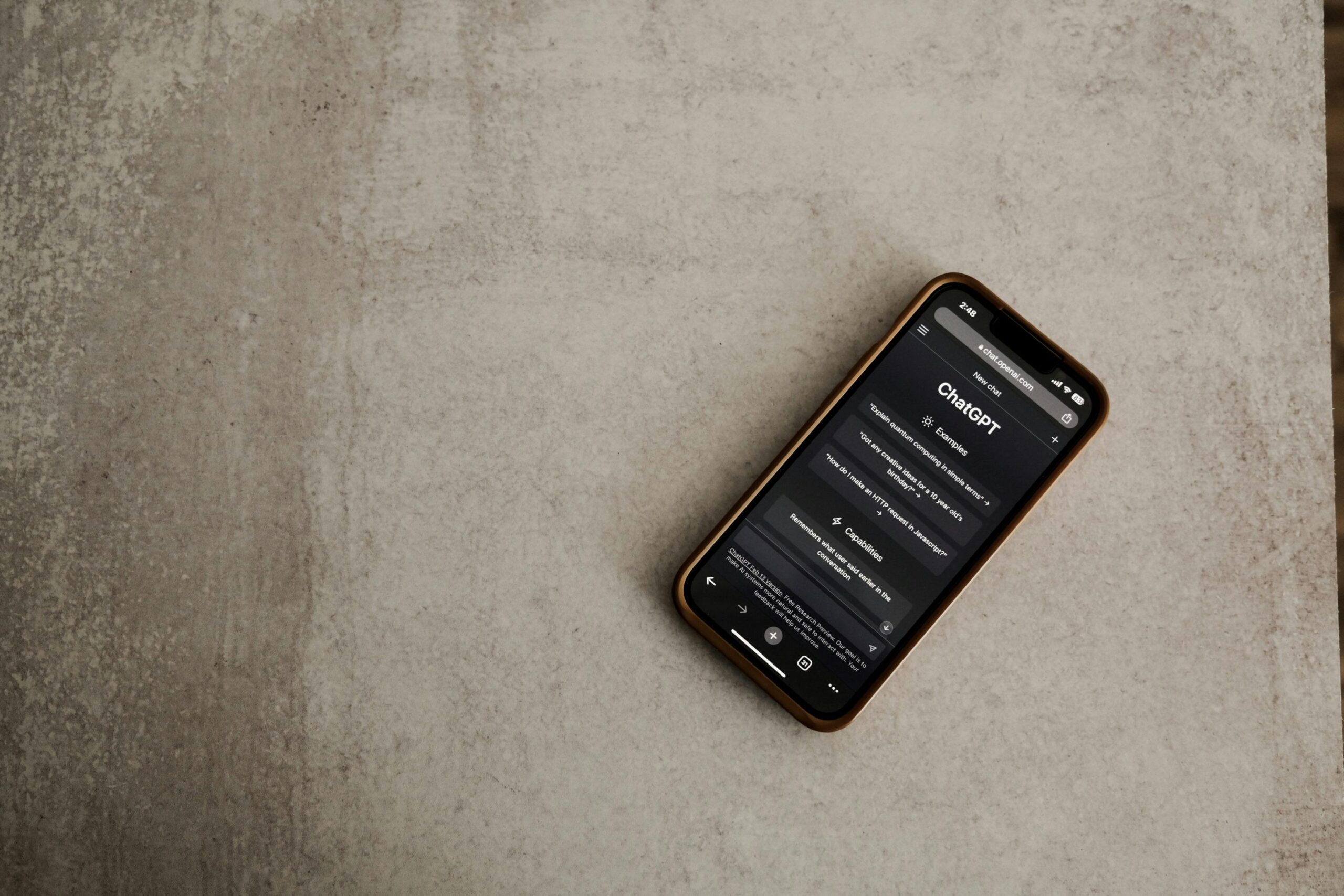 Un smartphone con una pantalla negra que muestra texto yace boca arriba sobre una superficie texturizada de color gris claro.