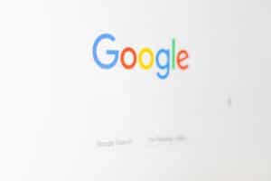 La pantalla de un ordenador muestra la página principal de Google con el logotipo de Google encima de la barra de búsqueda y dos botones de búsqueda debajo.