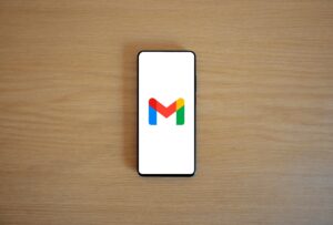 Se coloca un smartphone con el logotipo de Gmail en la pantalla sobre una superficie de madera.
