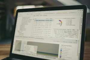 La pantalla de un portátil muestra herramientas de desarrollo de software con código, un gráfico circular y gráficos de análisis del rendimiento visibles en la interfaz.