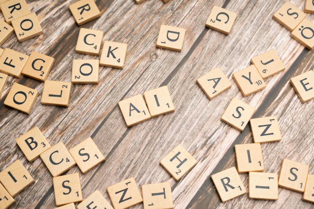 Fichas de letras de Scrabble esparcidas sobre una superficie de madera, con las letras "A" e "I" colocadas juntas en el centro.
