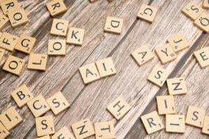 Fichas de letras de Scrabble esparcidas sobre una superficie de madera, con las letras "A" e "I" colocadas juntas en el centro.