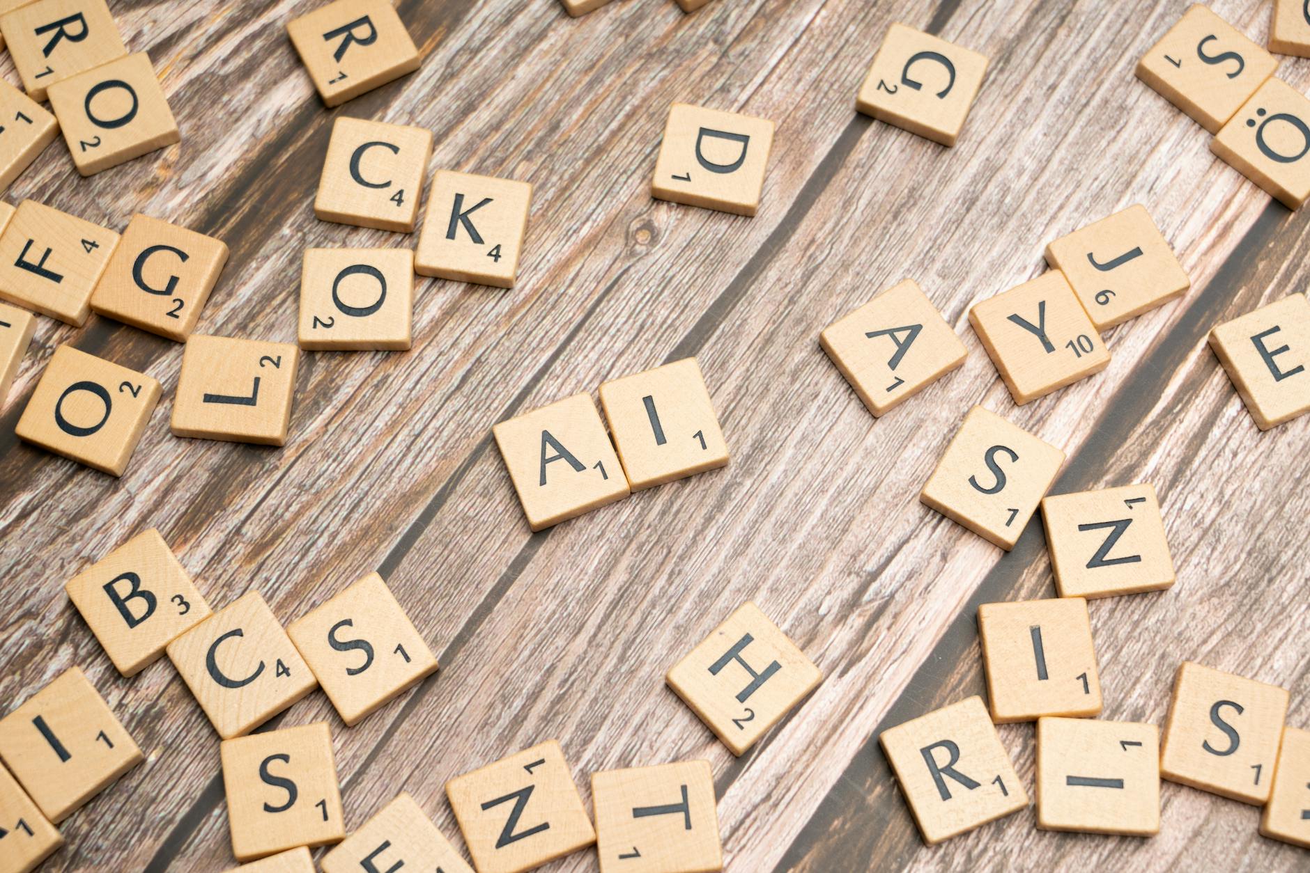 Fichas de letras de Scrabble esparcidas sobre una superficie de madera, con las letras "A" e "I" colocadas juntas en el centro.